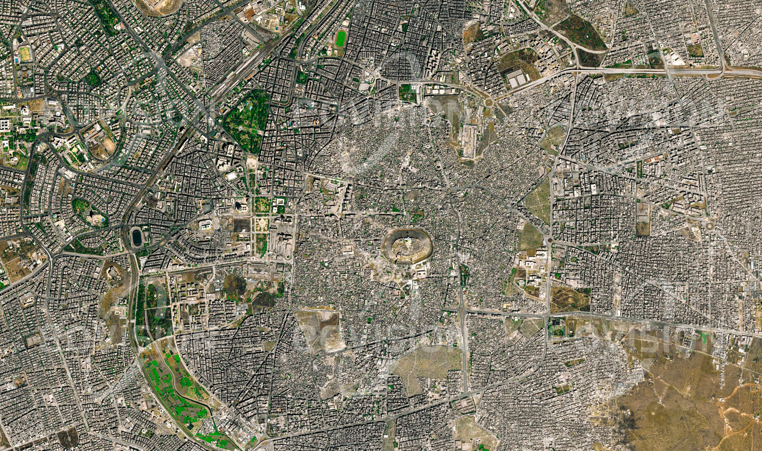 Das Satellitenbild 'ALEPPO 2015, Syrien' ist dem Bildband "Cities - Brennpunkte der Menschheit" entnommen. Aleppo hat als eine der ältesten Städte der Welt im Lauf der Jahrhunderte zahlreiche Konflikte erlebt. Einst einer der Ausgangspunkte der Seidenstraße, ist die Stadt für die mächtige Zitadelle und die Souks der Altstadt bekannt. Vor dem Ausbruch des syrischen Bürgerkriegs war Aleppo die bevölkerungsreichste Stadt Syriens. Im Verlauf des syrischen Bürgerkriegs, der 2012 begann, wurden mehr als 13.500 Einwohner der Stadt getötet, deutlich mehr flohen. Teile der mittelalterlichen Altstadt, darunter der Großteil des Al-Madina Souks und der Großen Moschee Aleppos, wurden durch Bombardements und Brä