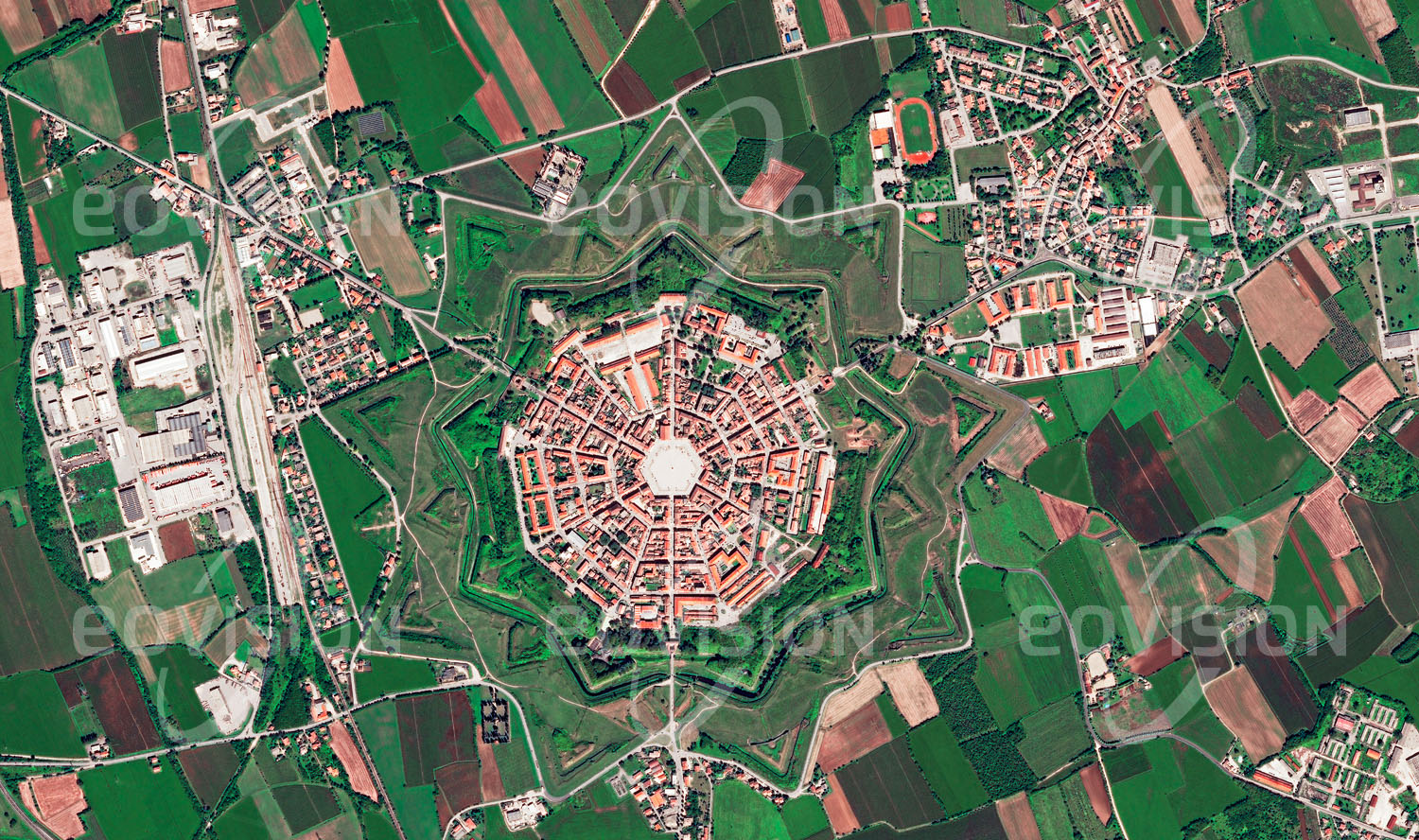 Das Satellitenbild 'PALMANOVA, Italien' ist dem Bildband "Cities - Brennpunkte der Menschheit" entnommen. Palmanova mit seinem neuneckigen, sternfömigen Grundriss aus dem 16. Jahrhundert ist wohl der bekannteste Fall einer Idealstadt. Form und Funktion, in diesem Fall der Verteidigungsanlagen, ergänzen einander vorbildlich.