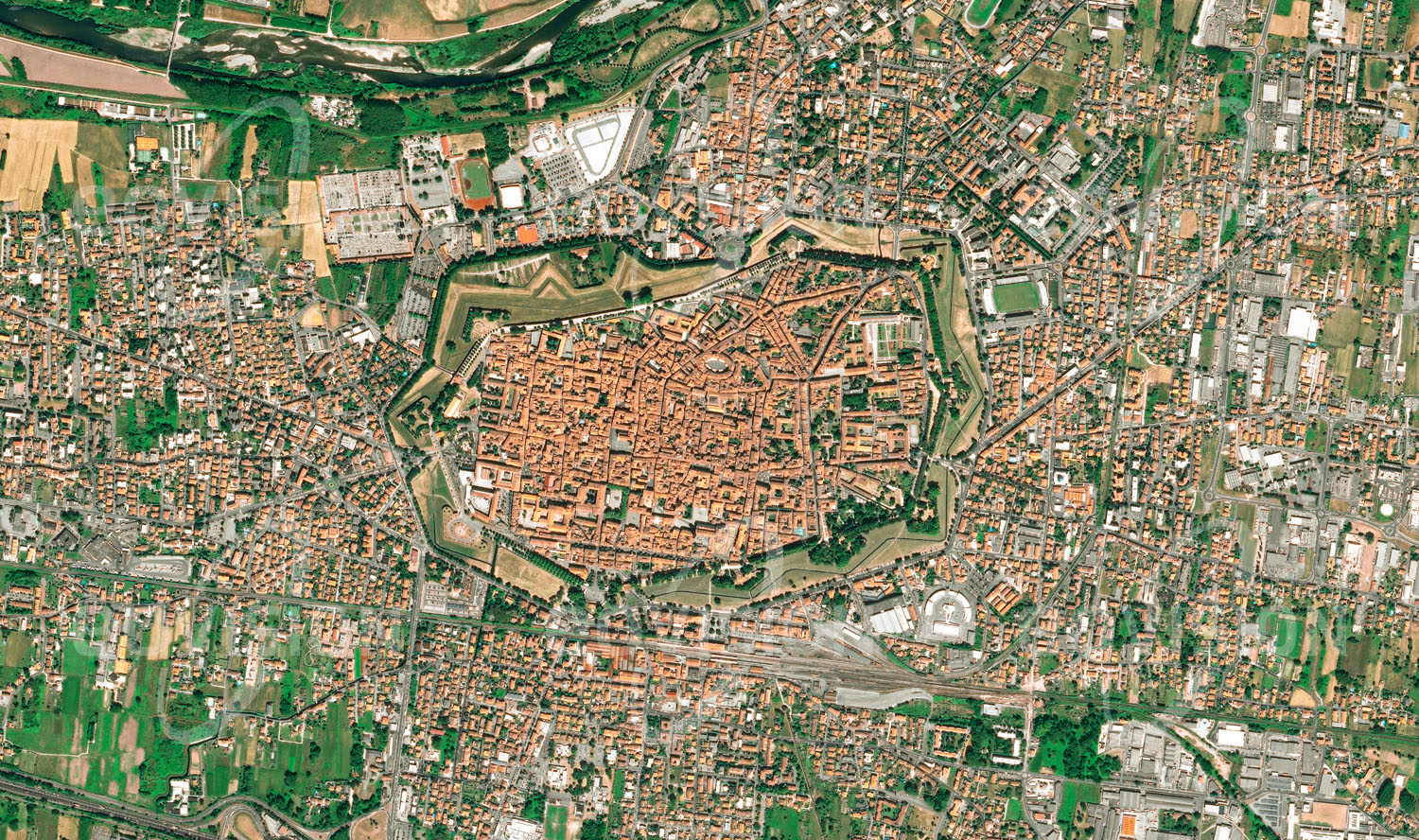 Das Satellitenbild 'LUCCA, Italien' ist dem Bildband "Cities - Brennpunkte der Menschheit" entnommen. Die von vier Stadttoren durchbrochene Befestigungsanlage von Lucca wird seit Anfang des 19. Jahrhunderts als Promenade rund um den historischen Stadtkern genutzt, der um den Innenhof eines römischen Amphitheaters angeordnet ist. Mit ihren großen Plätzen, romanischen Kirchen und mittelalterlichen Türmen ist die Stadt in der Toskana ein beliebtes Ziel für Touristen