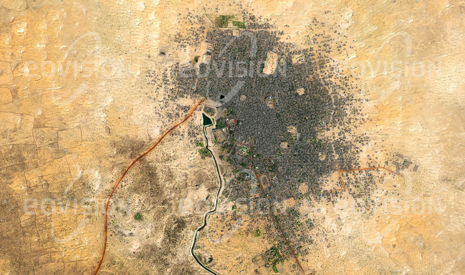 Das Satellitenbild 'TOMBOUCTOU, Mali' ist dem Bildband "Human Footprint - Satellitenbilder dokumentieren menschliches Handeln" entnommen. Die nahe dem Niger gelegene Stadt in der Wüste bildete über Jahrhunderte das Zentrum des Handels durch die Sahara. Zuletzt hatte Timbuktu unter politisch motivierten militä­rischen Auseinandersetzungen zu leiden, in deren Verlauf zahlreiche Kulturdenkmäler der Stadt, insbesondere Grabstätten islamischer Scheichs und Gelehrter, zerstört wurden.