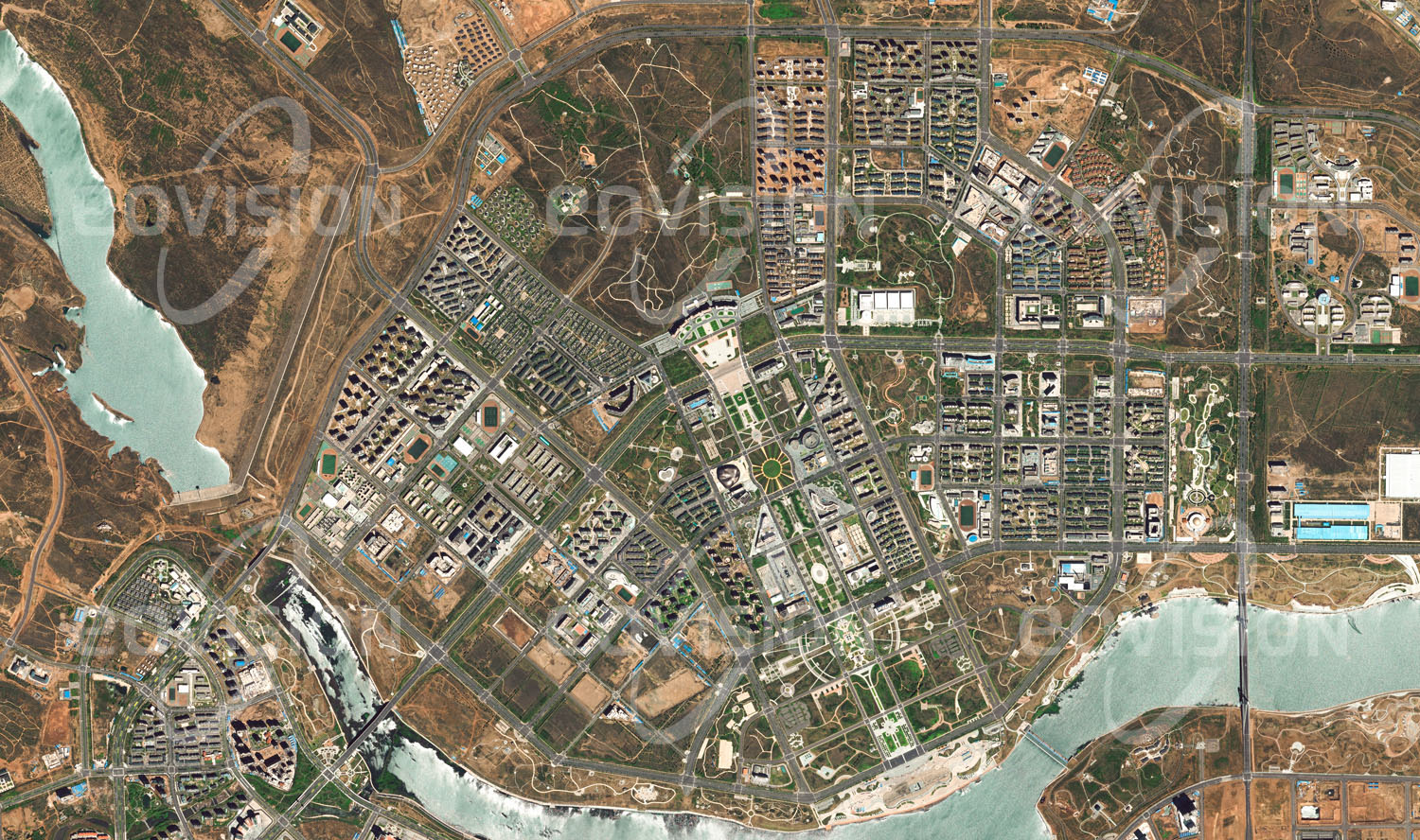 Das Satellitenbild 'KANGBASHI, China' ist dem Bildband "Cities - Brennpunkte der Menschheit" entnommen. ls im Jahr 2000 bei Dongsheng in der Inneren Mongolei, China, Kohle- und Gasvorkommen entdeckt wurden, setzte ein Aufschwung ein, der die Stadt rasch wachsen ließ. Um die erwartete Bevölkerungszunahme zu bewältigen, wurde 30 Kilometer von Dongsheng mit Kangbashi ein neuer Stadtteil erbaut. Auf 32 Quadratkilometern entstand zunächst für 300.000, später für fast 1 Million Menschen eine komplette Stadt. Diese wird allerdings von den Menschen nur zögerlich angenommen, wie die leeren Straßen im Satellitenbild zeigen. Bis 2015 waren erst etwa 100.000 Menschen in diese „Geisterstadt“ gezogen.