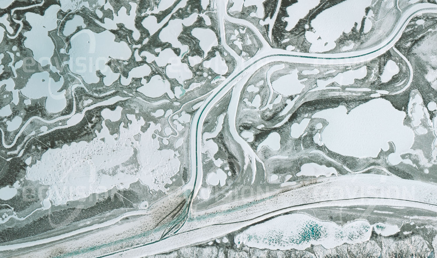 Das Satellitenbild 'INUVIK, Kanada' ist dem Bildband "Human Footprint - Satellitenbilder dokumentieren menschliches Handeln" entnommen. Im Winter werden die eisbedeckten arktischen Flüsse als Autobahnen genutzt, deren Fahrbahnen im Frühling durch dunkles, blankes Eis erkennbar sind.