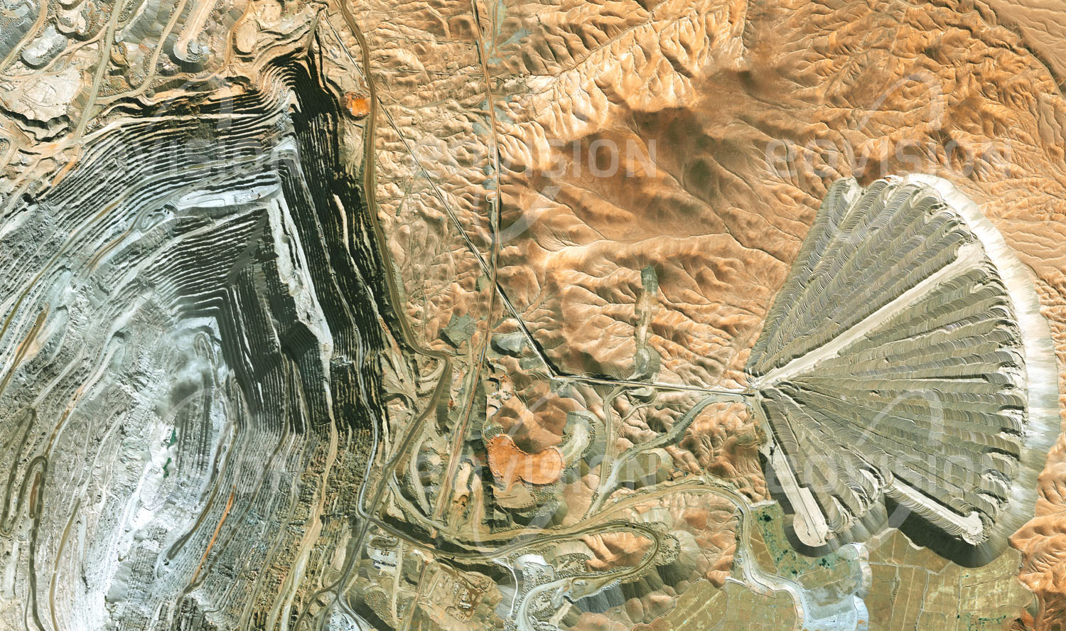 Das Satellitenbild 'CALAMA, Chile' ist dem Bildband "Human Footprint - Satellitenbilder dokumentieren menschliches Handeln" entnommen. In der chilenischen Wüste Atacama befindet sich die nach der Escondida-Mine weltweit produktivste Kupfermine Chuquicamata. Die enormen Abraummengen der mit 4,3 Kilo­metern Länge, 3 Kilometern Breite und mehr als 900 Metern Tiefe weltgrößten Kupfermine werden unweit der Grube fächerförmig wieder angehäuft. Bisher wurden in Chuquicamata etwa 30 Millionen Tonnen Kupfer gefördert.