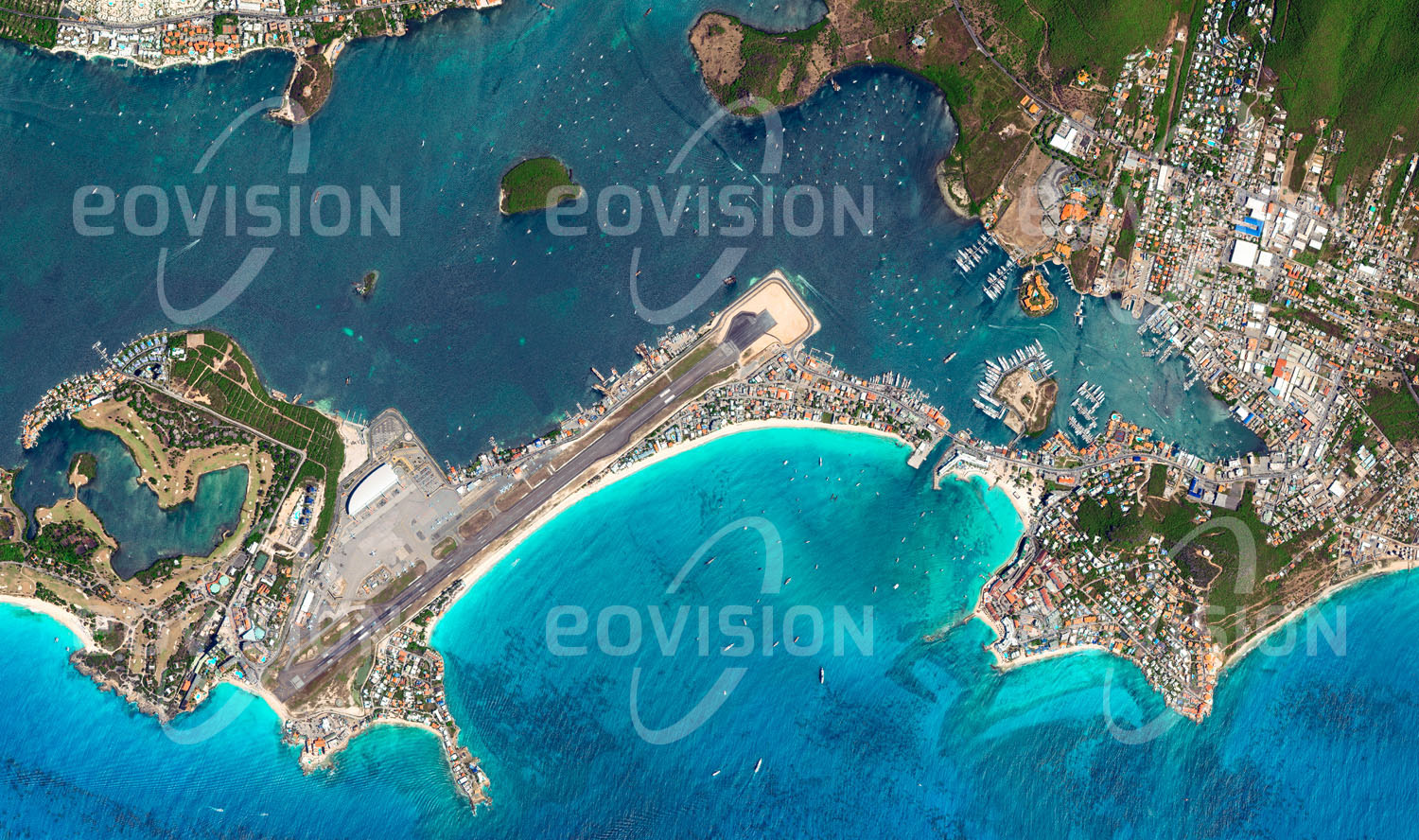 Das Satellitenbild 'SINT MAARTEN, Niederlande' ist dem Bildband "Human Footprint - Satellitenbilder dokumentieren menschliches Handeln" entnommen. Starts und Landungen auf dem Princess Juliana Flughafen der kleinen Antilleninsel St. Martin führen spektakulär direkt über die Köpfe der Badenden am Maho Beach hinweg.