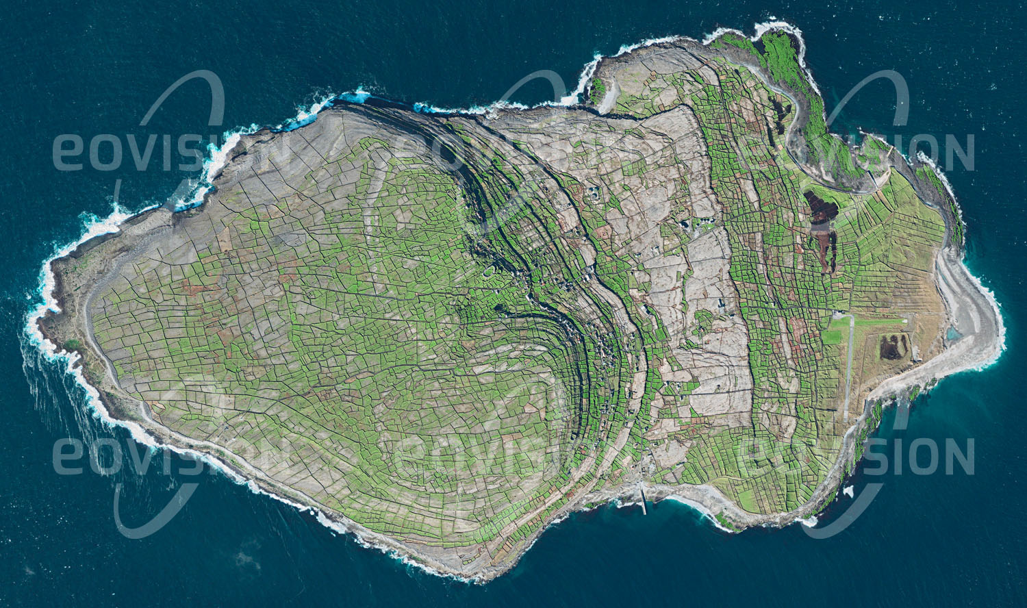 Das Satellitenbild 'INISHMAAN, Irland' ist dem Bildband "Human Footprint - Satellitenbilder dokumentieren menschliches Handeln" entnommen. Inishmaan ist eine der Aran-Inseln, die vor der Galway Bay an der Westküste Irlands liegen. Die durch eiszeitliche Gletscher geformte Felseninsel ist mit einem dichten Netz alter Steinmauern überzogen, die den Boden vor Erosion schützen. So konnte nach und nach durch Auftragen von Algen Humus aufgebaut und die Insel bewirtschaftet werden. Heute leben noch 160 Menschen auf Inishmaan.