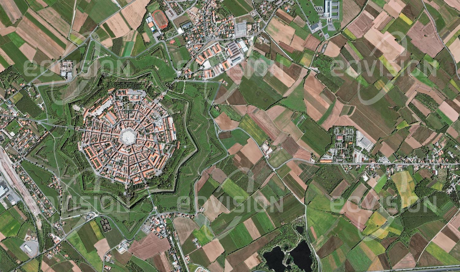 Das Satellitenbild 'PALMANOVA, Italien' ist dem Bildband "Human Footprint - Satellitenbilder dokumentieren menschliches Handeln" entnommen. Die sternförmige Struktur der im 16. Jahrhundert angelegten Festungsstadt Palmanova mit drei großen Stadttoren und dem umgebenden Wassergraben hat sich bis heute erhalten.