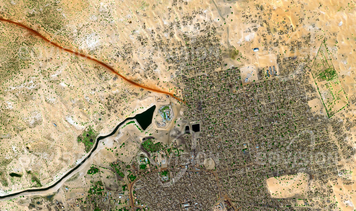 Das Satellitenbild 'TOMBOUCTOU, Mali' ist dem Bildband "Human Footprint - Satellitenbilder dokumentieren menschliches Handeln" entnommen. Um das Jahr 1200 im heutigen Mali nahe dem Niger am Südrand der Sahara gegründet, war die Stadt über Jahrhunderte ein wichtiges Zentrum des Handels mit Salz, Gold, Elfenbein und Sklaven. Heute ist sie für ihre historischen Bauten in der typischen Lehmbauweise mit Flachdächern bekannt, sowie für die Moscheen und die Mausoleen islamischer Gelehrter aus dem 16. Jahrhundert. Wegen der Bedeutung der Stadt für die islamische Kultur in Afrika wurde Timbuktu auf die Welterbeliste gesetzt und nach islamistischen Angriffen und Zerstörungen 2012 auf die Liste gefährdeten Welterbes.