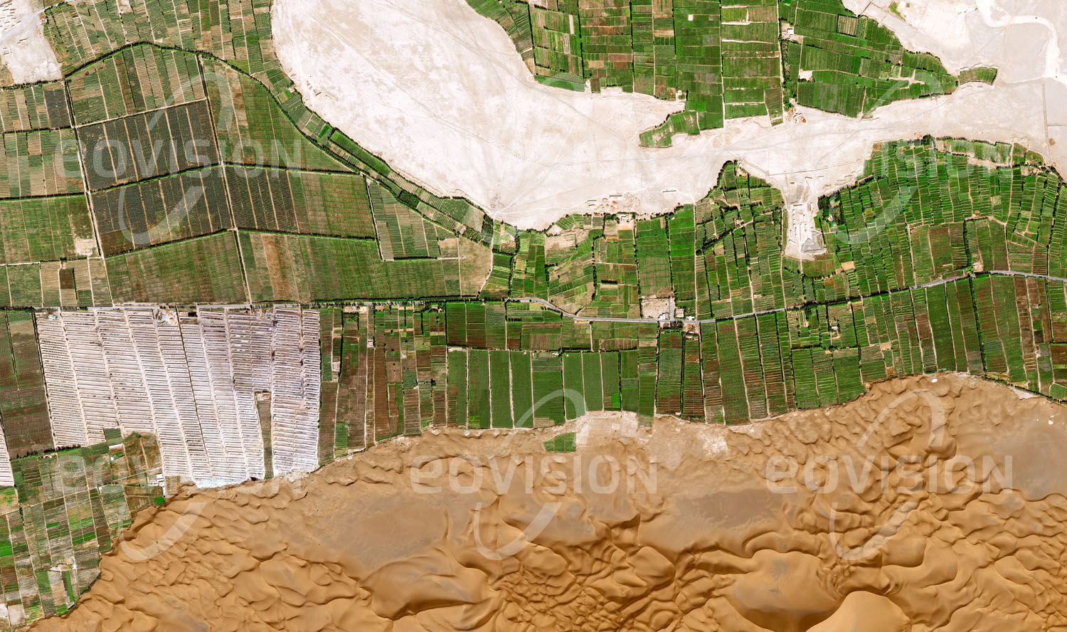 Das Satellitenbild 'DADONGHU, China' ist dem Bildband "Human Footprint - Satellitenbilder dokumentieren menschliches Handeln" entnommen. Die regelmäßigen Strukturen der bewässerten landwirtschaftlichen Flächen stehen in scharfem Kontrast zu den Dünen der direkt daran anschließenden Wüste.