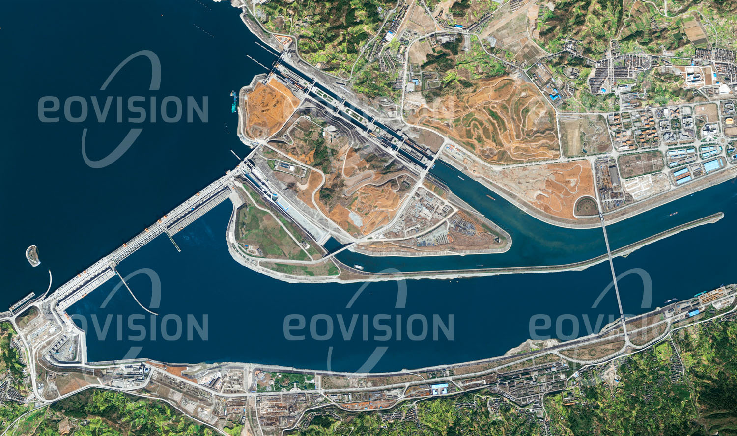 Das Satellitenbild 'LIJIAWAN, China' ist dem Bildband "Human Footprint - Satellitenbilder dokumentieren menschliches Handeln" entnommen. Die Staumauer des 2008 in Vollbetrieb genommenen Drei-Schluchten-Damms staut den Jangtsekiang über 600 Kilometer zurück. Neben der Gewinnung von jährlich mehr als 80 Terawattstunden elektrischer Energie soll der Damm auch den Hochwasserschutz und die Schiffbarkeit des Flusses verbessern. Dem wirtschaftlichen Nutzen stehen gravierende ökologische und soziale Probleme für die ursprünglichen Bewohner des nun überfluteten Gebiets gegenüber.