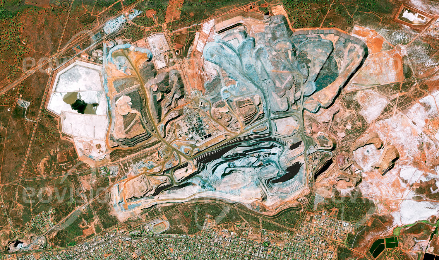 Das Satellitenbild 'KALGOORLIE, Australien' ist dem Bildband "Human Footprint - Satellitenbilder dokumentieren menschliches Handeln" entnommen. Unterschiedliche Farbtöne kennzeichnen die Gesteinsschichten der Super Pit Mine nahe der Stadt Kalgoorlie im australischen Outback, wo jährlich etwa 25 Tonnen Gold gefördert werden.