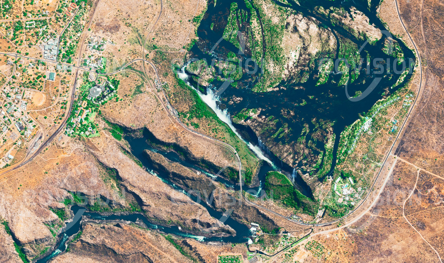 Das Satellitenbild 'VICTORIA FALLS, Sambia' ist dem Bildband "Wasser - Entdeckung des Blauen Planeten" entnommen. An der Grenze zwischen Sambia und Simbabwe rauscht der Sambesi über die Victoriafälle talwärts. Der nach Fläche, also dem Produkt aus der Höhe von fast 110 Metern und der Breite von mehr als 1700 Metern, weltweit größte Wasserfall heißt in einer lokalen Sprache sehr passend »Donnernder Rauch«.