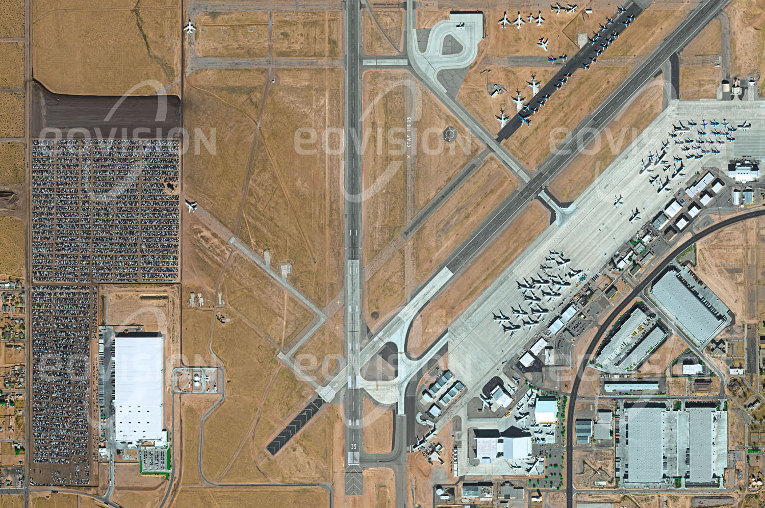 Das Satellitenbild 'ADELATO, USA' ist dem Bildband "New Human Footprint - Unsere Welt im Umbruch" entnommen. Der frühere Militärflughafen George Air Force Base wurde 1993 aufgelassen und zum Southern California Logistics Airport umgewandelt. Dieser hat sich zu einem wichtigen Güterverkehrsknotenpunkt entwi­ckelt, über den 60 Prozent der Güter laufen, die von und nach Südkalifornien geliefert werden. Daneben werden hier Flugzeuge gewartet, gelagert und demontiert. Ein Teil des Geländes wurde als Folge des Dieselskandals im Jahr 2015 als Parkplatz für nicht verkäufliche Autos genutzt.