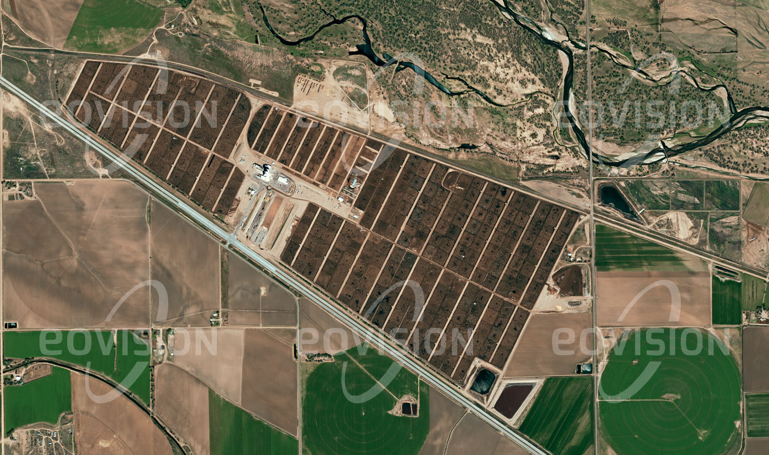 Das Satellitenbild 'KERSEY, USA' ist dem Bildband "one earth - Limitierte Ausgabe" entnommen. Inmitten landwirtschaftlicher Anbauflächen liegt das Kuner-Feedlot am South Platte River in Colorado, das mit einer Kapazität von 100.000 Tieren zu den größeren Einrichtungen dieser Art gehört. Als Feedlots werden vor allem in den USA Viehmastbetriebe bezeichnet, in denen Rinder mittels speziellen Futters innerhalb von drei bis vier Monaten auf ihr Schlachtgewicht gebracht werden. Bei normaler Ernährung würden sie dafür drei Jahre benötigen.