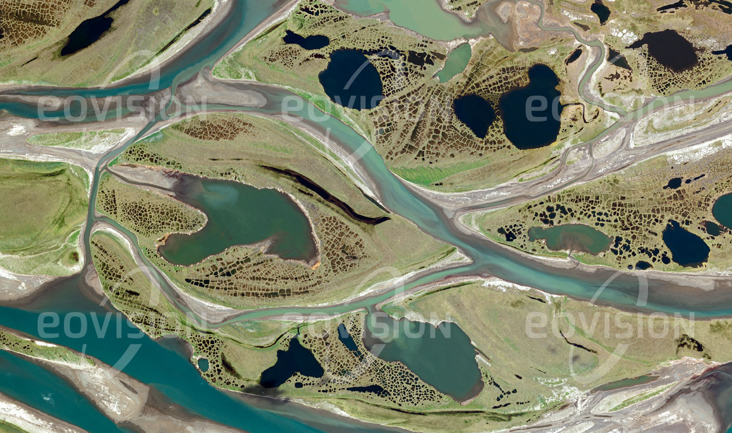 Das Satellitenbild 'COLVILLE RIVER, USA' ist dem Bildband "Untouched Nature - Naturlandschaften in Satellitenbildern" entnommen. Nicht weit von den Ölförderanlagen der Prudhoe Bay entfernt bilden sich im flachen Flussbett des Colville Rivers Inseln, die ih­rerseits durch ein dichtes Muster kleiner Seen bedeckt sind. Die feinen, netzartigen Strukturen sind eine Folge des wiederholten Gefrierens und Auftauens des wasserreichen Bodens. Im Winter wird der gefrorene Fluss auch als Eisstraße für die Versorgung der nördlich liegenden Siedlungen genützt. Karibus, Wölfe und Grizzlybären, aber auch die weltweit höchste Dichte brütender Raubvögel sind hier zu finden.