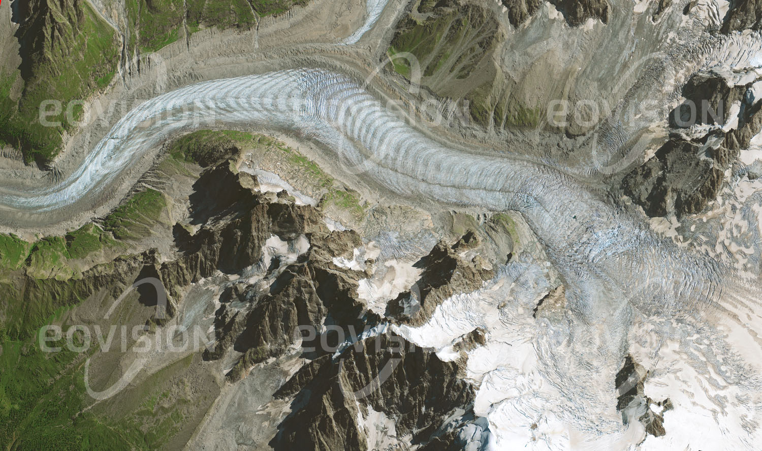 Das Satellitenbild 'MER DE GLACE, Frankreich' ist dem Bildband "Untouched Nature - Naturlandschaften in Satellitenbildern" entnommen. Der vom Mont Blanc-Massiv Richtung Chamonix fließende Gletscher zeigt charakteristische Querstreifen (Ogiven), die durch Abschmelzen jüngeren Eises entstehen und Jahresringen entsprechen.