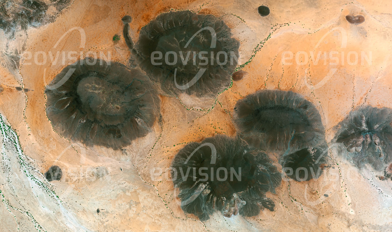 Das Satellitenbild 'JABAL TELJO, Sudan' ist dem Bildband "Untouched Nature - Naturlandschaften in Satellitenbildern" entnommen. Die dunklen Basaltstöcke alter Vulkane im Westsudan sind härter als das Umgebungsgestein und widerstehen daher der Erosion besser. Geringe Niederschläge erlauben eine nur karge Vegetation.