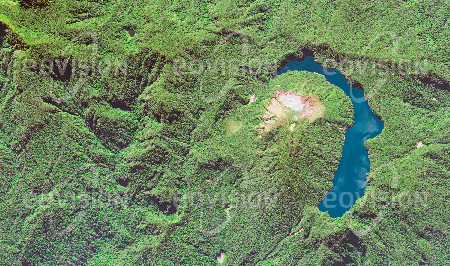 Das Satellitenbild 'LOLORU, Papua-Neuguinea' ist dem Bildband "Untouched Nature - Naturlandschaften in Satellitenbildern" entnommen. Ein halbmondförmiger See füllt einen älteren Krater des Vulkans auf der Bougainville Island, Teil des Salomonen-Archipels. Das Bergland der Insel ist von tropischem Regenwald bedeckt.