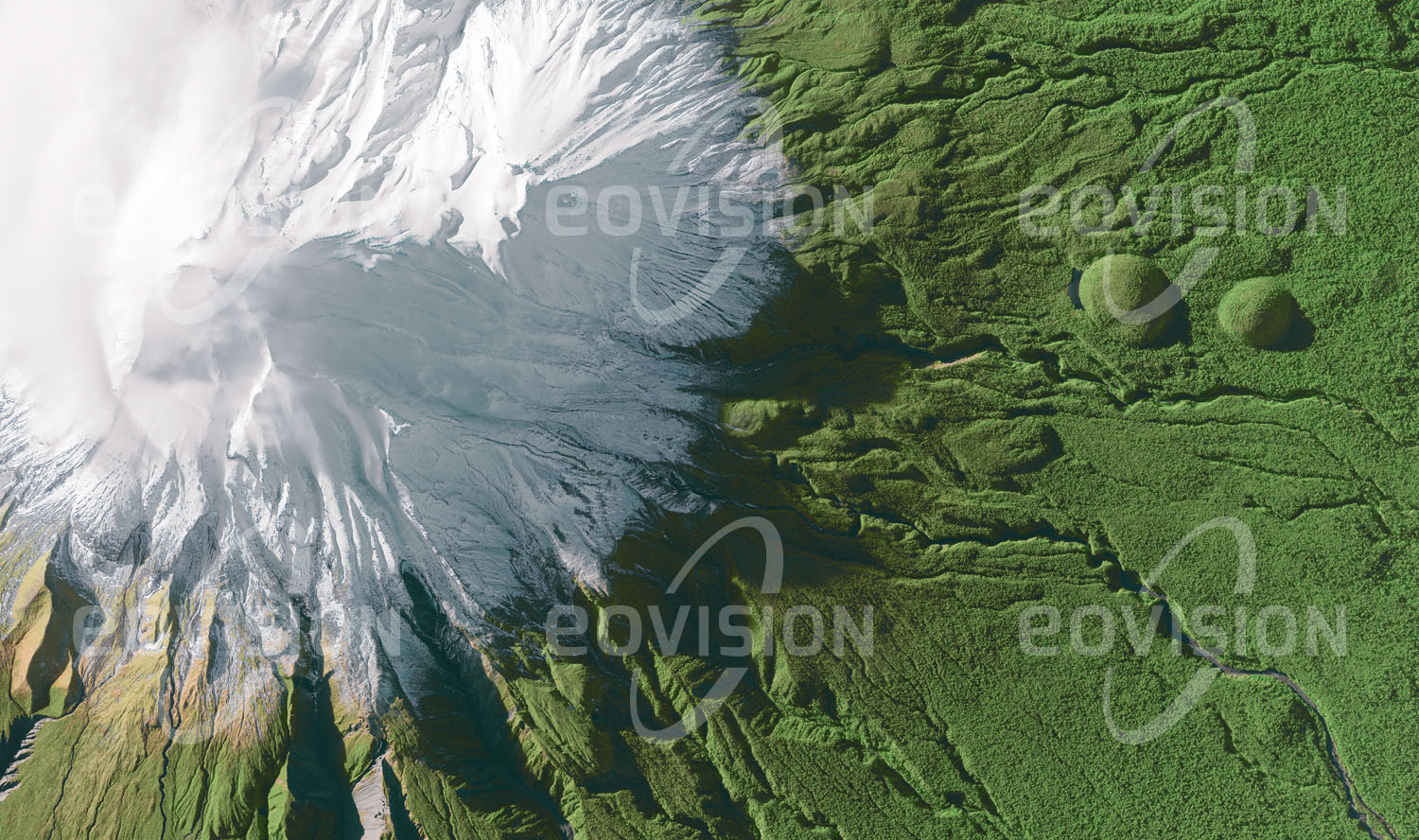 Das Satellitenbild 'MOUNT TARANAKI, Neuseeland' ist dem Bildband "Untouched Nature - Naturlandschaften in Satellitenbildern" entnommen. Der im Südwinter schneebedeckte, 2.518 Meter hohe Mount Taranaki auf der Nordinsel Neuseelands ist ein geologisch sehr junger Vulkan mit einer ausgeprägten Kegelform. Bereits im Jahr 1881 wurde um den Berg ein annähernd kreisförmiges Waldschutzgebiet errichtet, das seit 1900 den Hauptteil des Egmont-Nationalparks bildet. An der Grenze des Nationalparks geht der Regenwald abrupt in eine intensiv kultivierte Landschaft über.