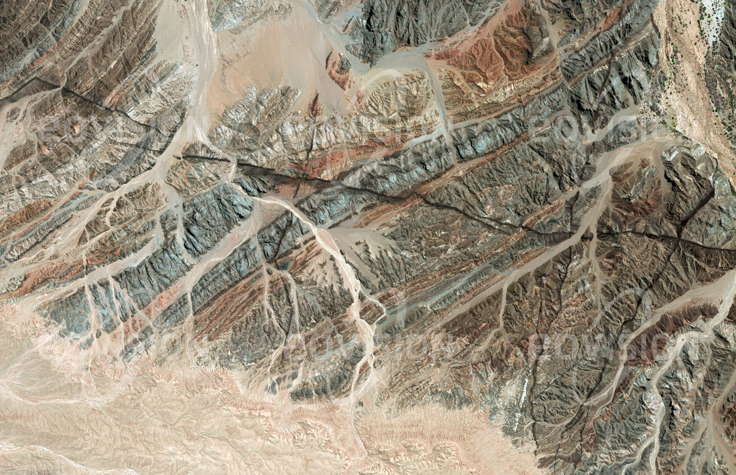 Das Satellitenbild 'GOANIKONTES, Namibia' ist dem Bildband "Wüsten - Lebensraum der Extreme" entnommen. Südlich des nur zeitweise Wasser führenden Swakop-Flusses erstreckt sich ein Felsgebiet, das im Satellitenbild ausgeprägte geologische Bruchlinien zeigt. Gut sichtbar ist die Faltung der Gesteinsschichten, die unter anderem aus granitischen Gneisen und Quarzit-Sedimenten bestehen. Die Landschaft trägt wegen ihrer lebensfeindlichen Bedingungen auch die Bezeichnung „Mondlandschaft“. Bekannt ist die Region auch für Funde von Uran und Boltwoodit, Kristallen eines seltenen Minerals. Nur 25 Kilometer weiter westlich liegt Swakopmund an der Mündung des Swakops in den Pazifik.