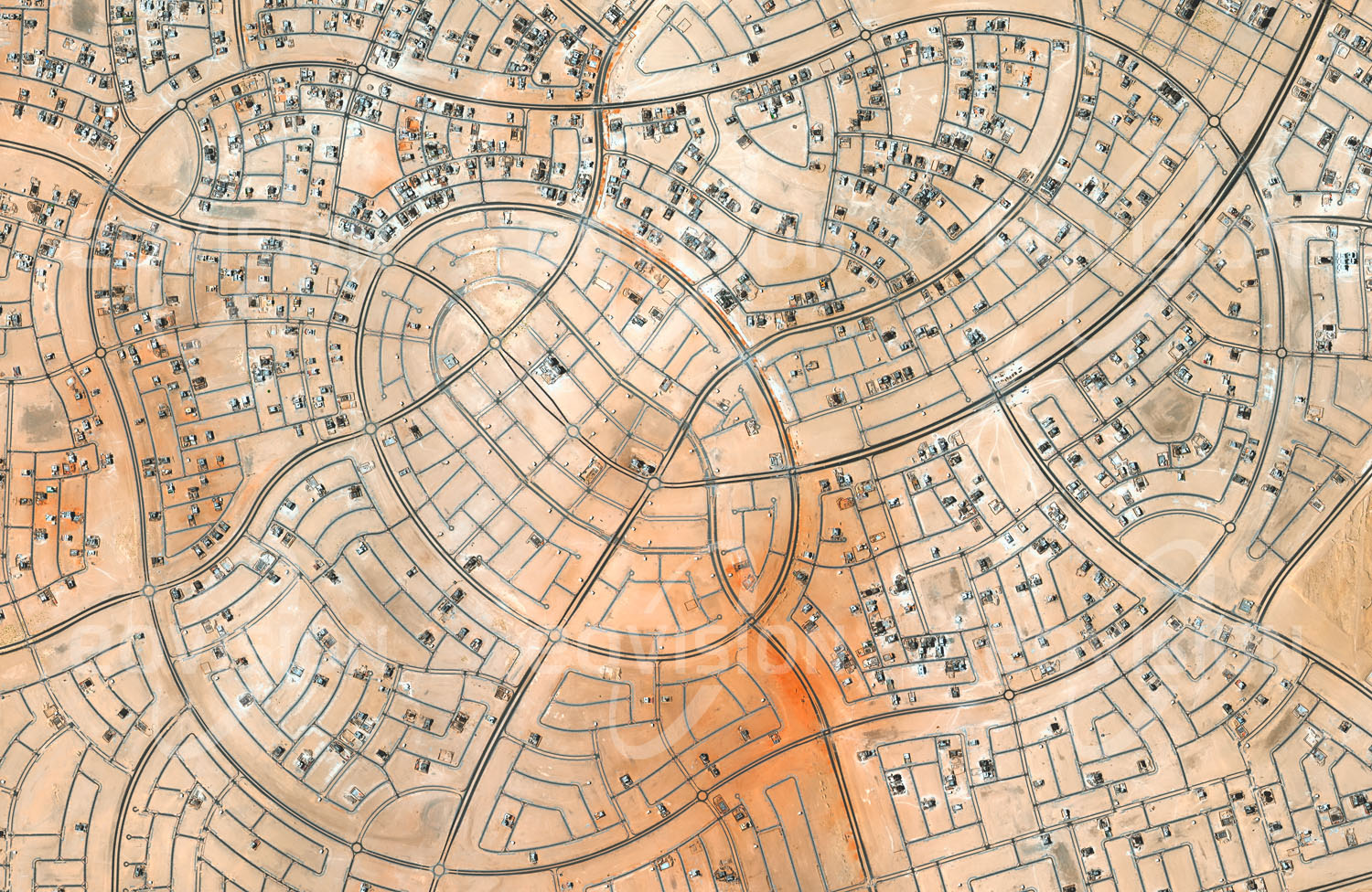 Das Satellitenbild 'AL-SHAMKHA, Vereinigte Arabische Emirate' ist dem Bildband "Wüsten - Lebensraum der Extreme" entnommen. Auf mehr als 40 Quadratkilometern Fläche wird ein neuer Stadtteil aus dem Boden gestampft, der für 130.000 Menschen Wohnraum bereitstellen wird. Der Plan des Viertels folgt einem aufgelockerten, von geschwungenen Straßenzügen dominierten Grundriss. Derartige organische Grundrisse werden oft als ansprechender empfunden als die üblichen Rechtecksraster und deshalb gerade für Wohnviertel immer häufiger angewendet.