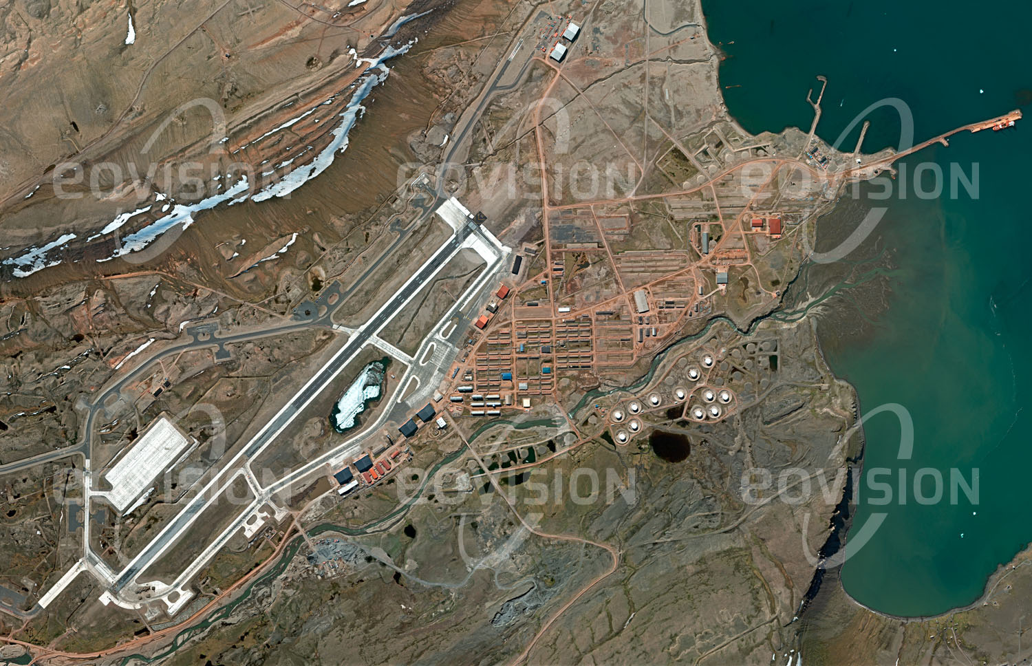 Das Satellitenbild 'THULE AIR BASE, Grönland' ist dem Bildband "Wüsten - Lebensraum der Extreme" entnommen. Thule bezeichnete in der griechischen und römischen Literatur den nördlichsten bekannten Ort, der heute nicht mehr sicher zu lokalisieren ist. Er diente als Namensgeber für eine US-amerikanische Luftwaffenbasis im Norden Grönlands. Auf fast 77° nördlicher Breite gelegen ist diese nur 1524 km vom Nordpol entfernt und war wegen der Nähe zur Sowjetunion im Kalten Krieg ein strategisch bedeutender Ort für die Luftaufklärung. Heute dient die Basis als Stützpunkt für das Air Force Space Command. 1968 kam es in der Nähe zum Absturz eines mit Nuklearwaffen bestückten Bombers.