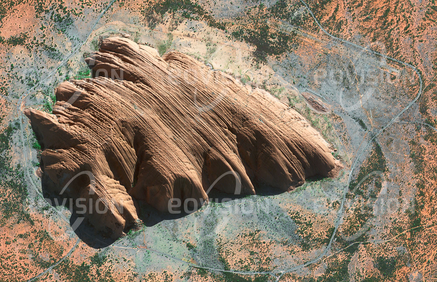 Das Satellitenbild 'ULURU, Australien' ist dem Bildband "Wüsten - Lebensraum der Extreme" entnommen. Der Uluru, auch unter der Bezeichnung Ayers Rock bekannt, ist der zweitgrößte Monolith der Erde. Von Wind und Sand geformt ragt er 348 Meter aus den Ausläufern der Großen Sandwüste im Herzen Australiens empor. Sein Farbenspiel in je nach Wetter und Sonnenlicht unterschiedlichen Rottönen hat den Felsen zu einer der bekanntesten Sehenswürdigkeiten Australiens gemacht. Nach den Aborigines, für die der Uluru ein heiliger Ort ist, stammt die Farbe vom Blut zweier riesiger Schlangen, die hier miteinander kämpften. Der Felsen ist auch wegen der hier gefundenen Felsmalereien Teil des UNESCO-Welterbes